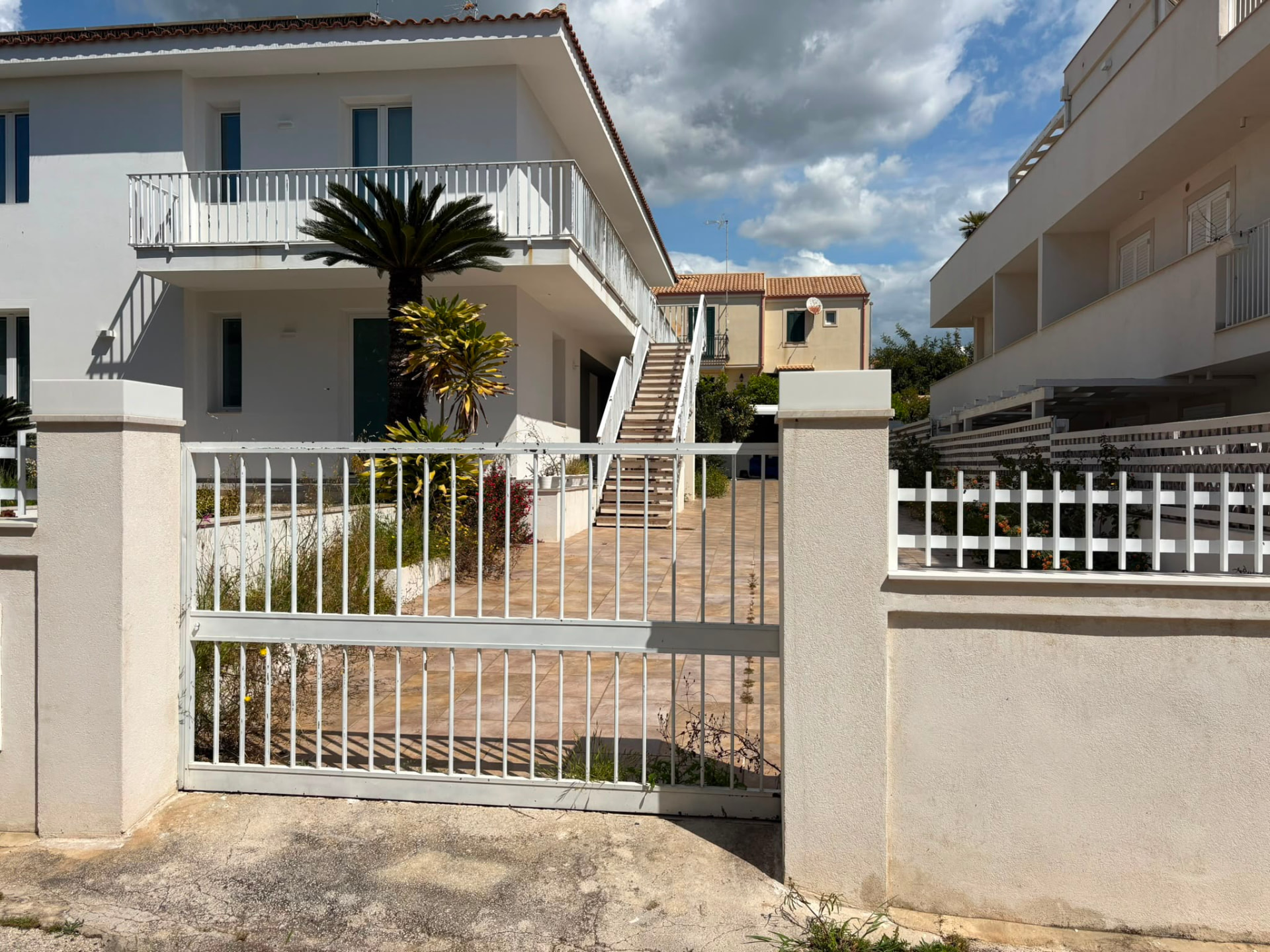 Esterno della casa vacanze Nicorooms con palma e cancello bianco